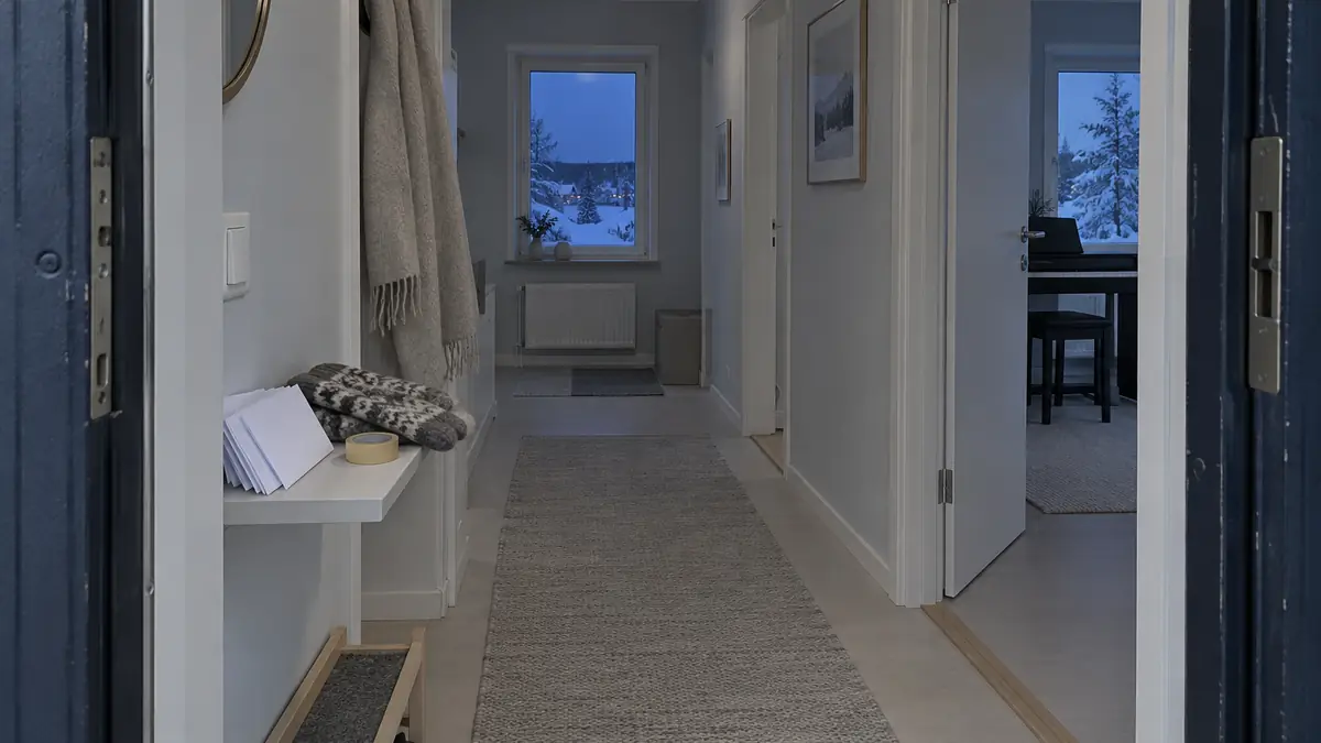 En hall med en hylla vid ytterdörren och ett digitalpiano längre in